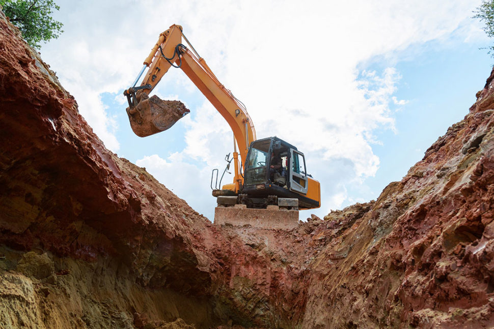 Excavator digging a trench. Work on the construction site.